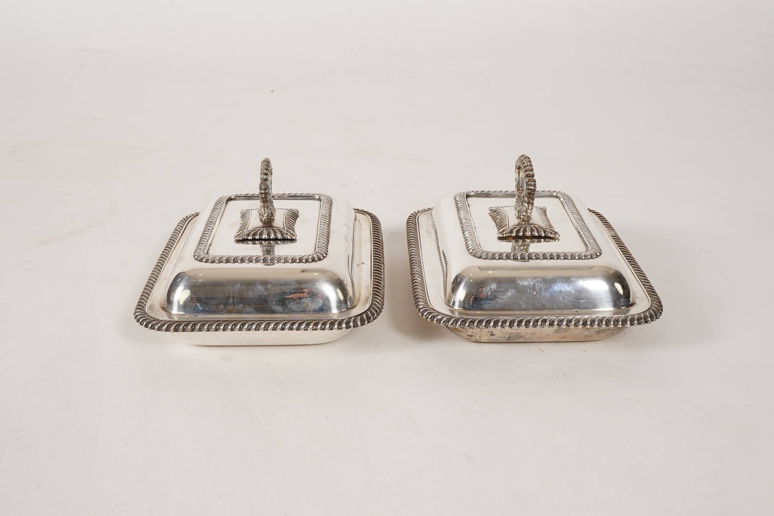 A matched pair of George V silver rectangular entrée dishes and covers, both with gadrooned borders and similar unmarked handles, Ellis & Co, Birmingham, 1923 and Ellis & Co, Birmingham, 1932, base 27.8cm, 108.3oz, exclu